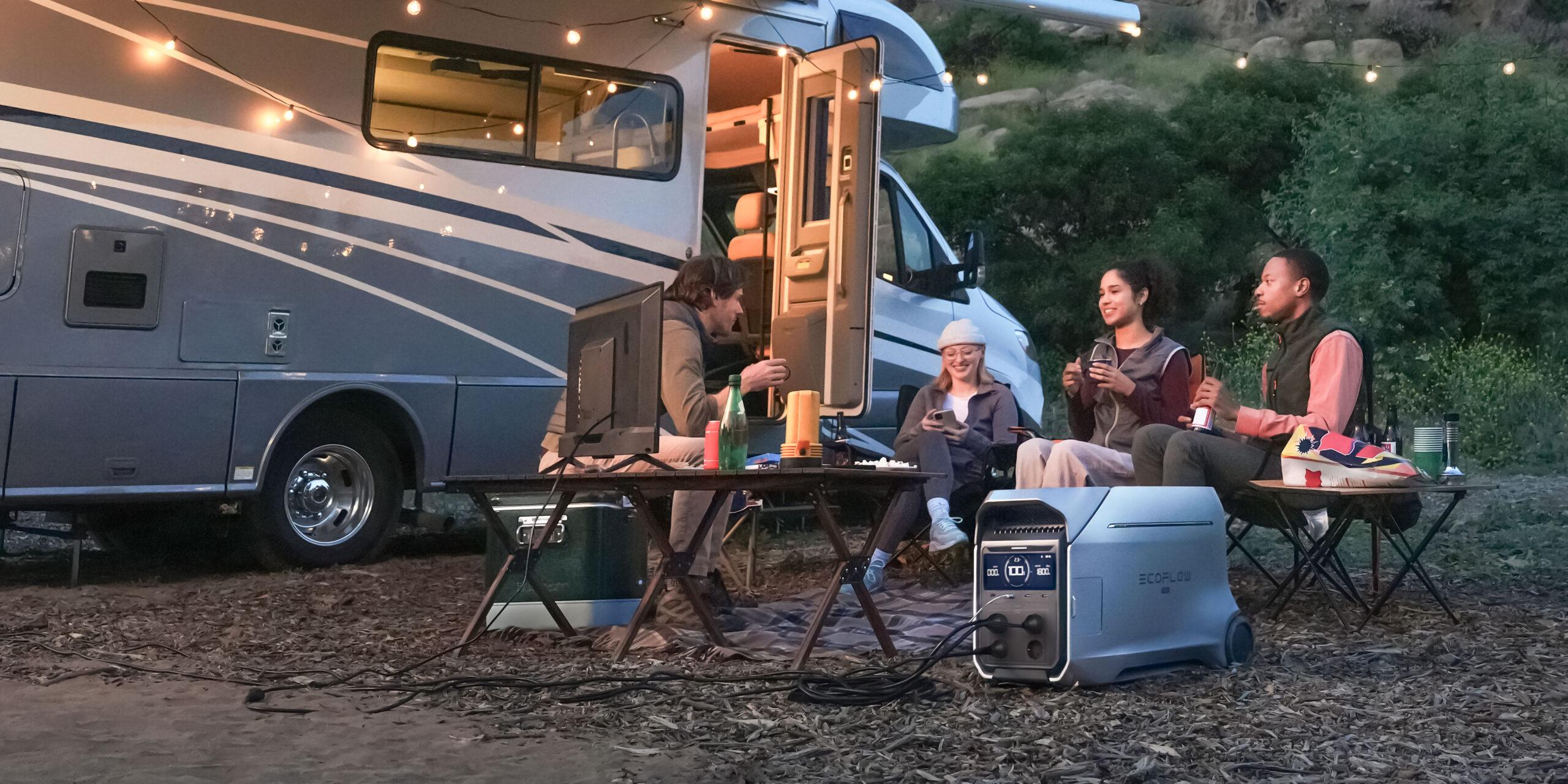 Familie sitzt vor Camper mit mobiler Energie und mobilen Geräten von Ecoflow, Delta am Fernseh angeschlossen.